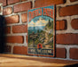 A vintage-style metal sign for Devil's Path in New York, featuring a scenic mountain landscape and trail directions.