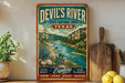 A vintage-style sign for Devil's River State Natural Area in Texas, featuring a scenic landscape with a river, cacti, and mountains.