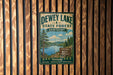A vintage metal sign for Dewey Lake State Forest in Kentucky, featuring a scenic landscape with pine trees, a lake, and mountains.