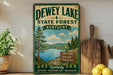 A vintage-style sign for Dewey Lake State Forest in Kentucky, featuring a scenic illustration of the lake surrounded by pine trees and mountains.