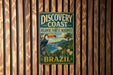 A vintage-style metal sign with a tropical bird and palm trees, advertising the Discovery Coast Atlantic Forest Reserve in Brazil.