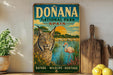 a vintage-style sign for Donana National Park in Spain, depicting a cat and a flamingo in a natural setting.
