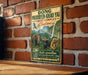 A vintage-style metal sign with text and illustrations of wildlife, including elephants, a monkey, and a waterfall, mounted on a brick wall.