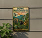 a vintage-style metal sign with a forest scene and various animals, including elephants, a monkey, and a bird, set against a backdrop of mountains and a waterfall.
