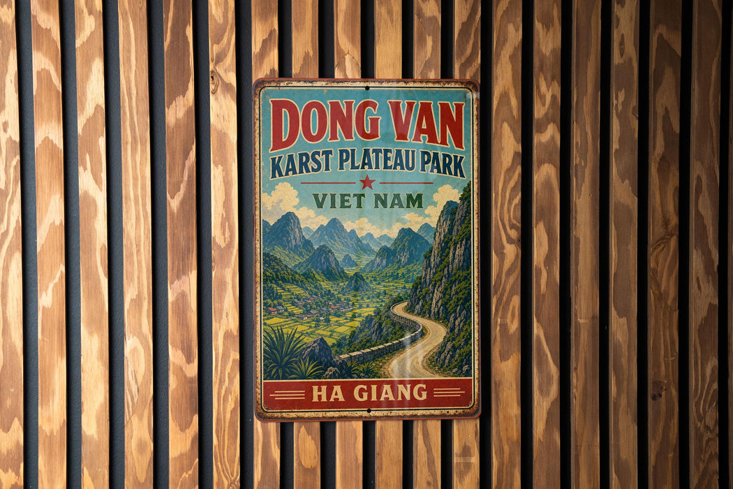 A vintage metal sign with a scenic mountain landscape and a winding road, mounted on a wooden wall.