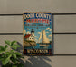 A vintage metal sign for Door County's Maritime Heritage Landscape, featuring a lighthouse and a sailboat on a body of water.