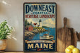 a vintage-style sign for Down East Coastal Heritage Landscape Maine, with a lighthouse and coastal scenery depicted.