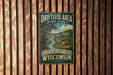 A vintage-style sign for the "Driftless Area Cultural Landscape" in Wisconsin, featuring a scenic landscape with a river and mountains.