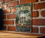 A vintage-style sign for the Dunleith Historic Inn in Mississippi, featuring a large illustration of a historic building surrounded by flowers.