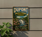 A vintage-style metal sign for DuPont State Recreational Forest, featuring a scenic image of a waterfall and pine trees.