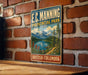 A vintage-style metal sign for E.C. Manning Provincial Park in British Columbia, Canada, featuring a scenic landscape with mountains, a lake, and pine trees.