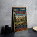 A vintage-style sign for Edsel & Eleanor Ford House, featuring a large illustration of the house and the Ford logo, is displayed on a gray countertop next to some black camera lenses.