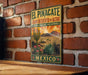 A vintage-style metal sign with a desert landscape and cacti, mounted on a brick wall.