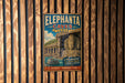A vintage-style metal sign advertising the Elephant Caves in India, featuring an illustration of a temple and a statue of a deity.