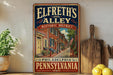 A vintage-style sign for Elfreth's Alley Historic District in Philadelphia, Pennsylvania, featuring an illustration of a street lined with brick houses and trees.