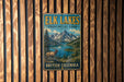 A vintage-style metal sign for the Elk Lakes Provincial Park in British Columbia, Canada, featuring a scenic mountain landscape with a lake and a deer.