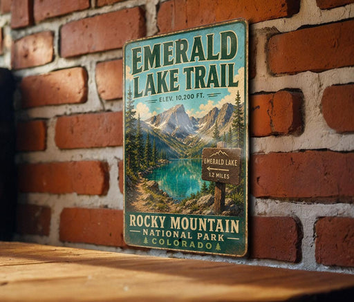 A vintage-style sign for the Emerald Lake Trail, featuring a scenic mountain landscape with a lake and pine trees.
