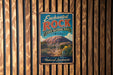 A vintage-style metal sign for the Enchanted Rock State Natural Area in Texas, featuring a desert landscape with a large rock formation and cacti.