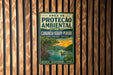 a vintage-style metal sign with a tropical landscape, including a boat on a river and a bird perched on a tree.