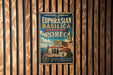 A vintage-style metal sign with text and an illustration of a building, mounted on a wooden wall.