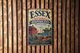 A vintage metal sign for the Essex National Heritage Area in Massachusetts, featuring an illustration of a lighthouse, a red brick building, and a boat on a body of water.