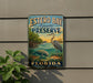 A vintage-style metal sign for Estero Bay Aquatic Preserve in Florida, featuring illustrations of various marine life and a seagull.