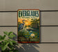 A vintage Everglades National Park sign is displayed on a wall, featuring a serene landscape with a heron, lily pads, and a sunset.