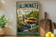 A vintage-style poster of Fallingwater, a landmark building in Pennsylvania, is displayed on a wall next to a wooden cutting board and some potted plants.