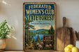 A framed vintage-style sign advertising the "Federated Women's Club State Forest" in Massachusetts, featuring a scenic landscape with pine trees, a lake, and mountains.