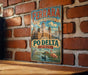 A vintage-style metal sign with the text "FERRARA CITY OF THE RENAISSANCE AND IT'S PO DELTA ITALY" is displayed on a brick wall.