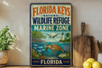 A vintage-style metal sign for the Florida Keys National Wildlife Refuge, featuring illustrations of marine life and a lighthouse, is displayed on a shelf next to a wooden cutting board and some lemons.