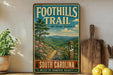 a vintage trail sign for the Foothills Trail in South Carolina, with a scenic mountain landscape and a path leading through the woods.