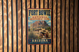A vintage-style sign for Fort Bowie National Historic Site in Arizona, featuring a desert landscape with a mountain and a cannon in the foreground.