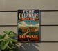 A vintage-style sign for Fort Delaware State Park, featuring an illustration of the fort and a flag, mounted on a wall.