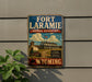 A vintage-style sign for the Fort Laramie National Historic Site in Wyoming, featuring a historical illustration of a wagon train and a prominent American flag.