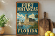 A vintage-style sign for Fort Matanzas National Monument in Florida, featuring a castle, palm trees, and a sailboat.