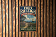 A vintage-style metal sign for the Fort Raleigh National Historic Site in North Carolina, featuring a ship and a wooden fence.