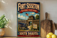 A vintage-style sign for Fortisset Historic State Park in South Dakota, featuring a cannon and a wooden fence, with a wooden paddle and a potted plant in the background.
