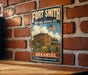 A vintage metal sign for the Fort Smith National Historic Site in Arkansas, featuring an illustration of a historic building and a wagon wheel.