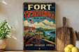 A vintage-style sign for Fort Ticonderoga, New York, featuring a cannon, a ship, and a scenic landscape.