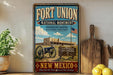 A vintage-style sign for Fort Union National Monument in New Mexico, featuring a cannon, a sign, and an American flag, with the text "Fort Union National Monument Preserving History Honoring Heritage" and "A PLACE WHERE THE PAST LIVES".