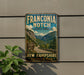 a vintage-style sign for Franconia Notch State Park, with a scenic mountain landscape and a road leading through the park.