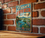 A vintage-style metal sign for Fraser River Delta, Canada, featuring a scenic illustration of the river, mountains, and wildlife.