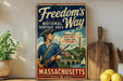 A vintage-style metal sign advertising the Massachusetts National Heritage Area, featuring a patriotic figure and a scenic landscape.