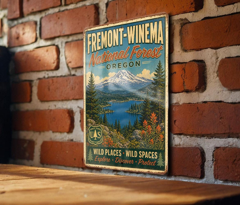 A vintage metal sign for the Fremont-Winema National Forest in Oregon, featuring a scenic landscape with a mountain, lake, and forest.