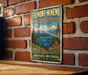 A vintage metal sign for the Fremont-Winema National Forest in Oregon, featuring a scenic landscape with a mountain, lake, and forest.