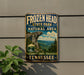 A vintage-style metal sign for Frozen Head State Park and Natural Area in Tennessee, featuring a scenic mountain landscape and the text "FROZEN HEAD STATE PARK AND NATURAL AREA EXPLORE. HIK. DISCOVER. TENNESSEE".