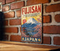 a vintage-style sign for Fujisan, a Japanese landmark, mounted on a brick wall.