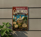 A vintage-style metal sign welcoming visitors to Gaineswood, Alabama, with a depiction of the town's landmarks and a banner that reads "Small Town Big Heart".