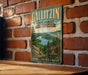 A vintage-style metal sign for Gallitzin State Forest in Pennsylvania, featuring a scenic landscape with a river and pine trees.